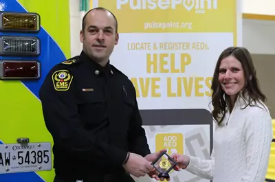 Chief Justin Lammers presents Tecumseh resident Andrea Ducharme with an Essex-Windsor EMS meritorious service coin.