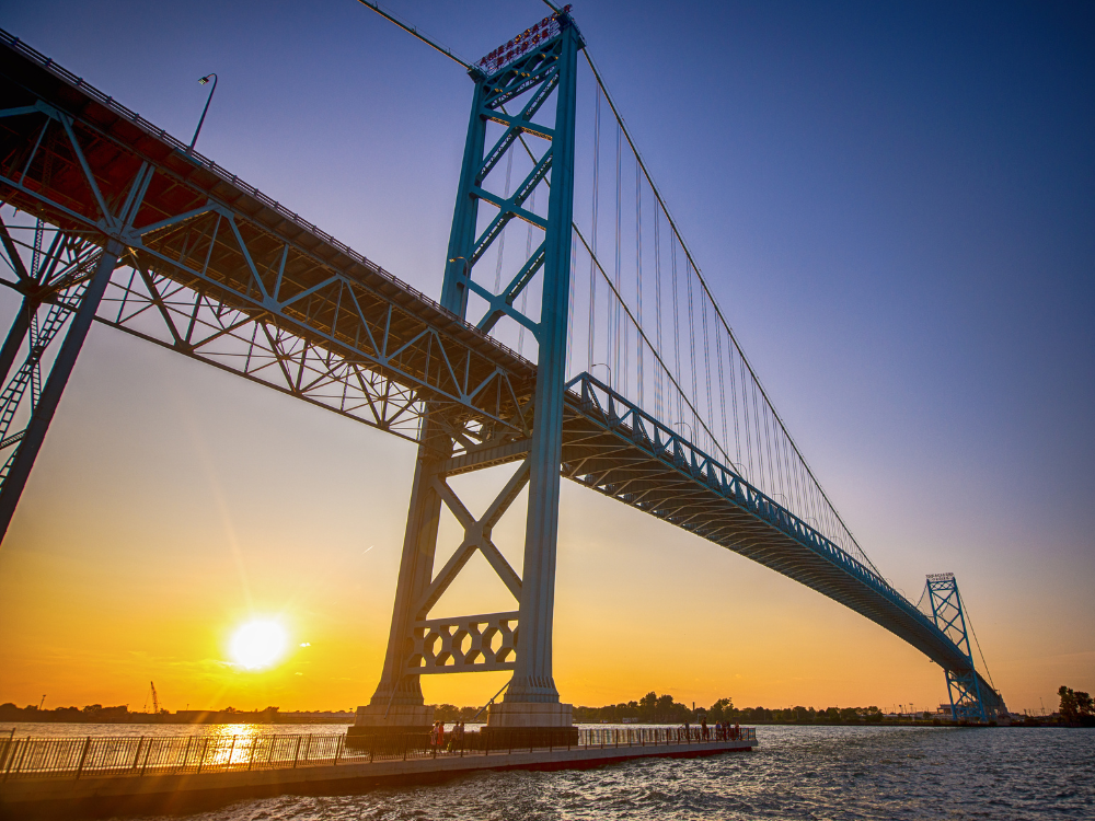 The sun sets behind the Ambassador Bridge.