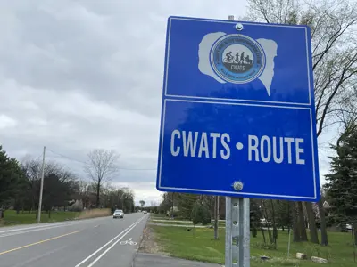 A CWATS sign next to a bike lane on a county road